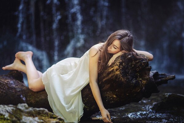 Una niña sueña en el bosque en un árbol reclinado. Sus piernas descansan después de una larga caminata