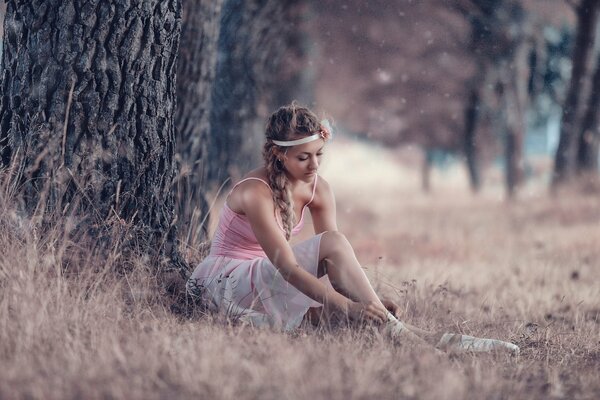 Mädchen Ballerina sitzt am Baum und trägt Spitzenschuhe