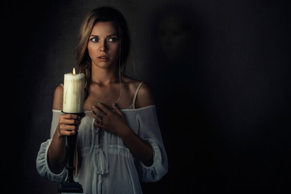 Una chica con una vela en la mano ve un fantasma y siente miedo