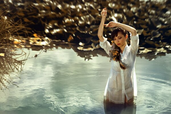 Ein Mädchen mit Blumen in Zöpfen und einem Nachthemd steht im Wasser