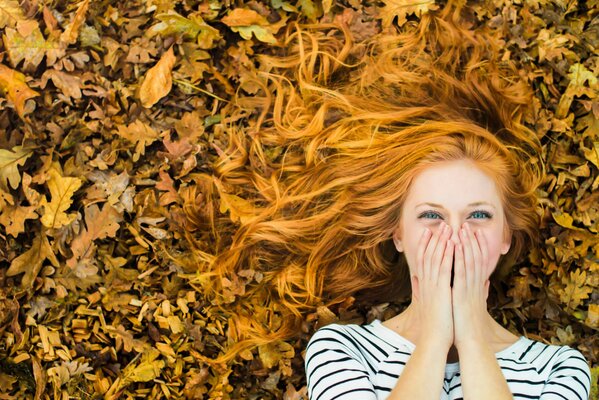 Red-haired girl in autumn foliage