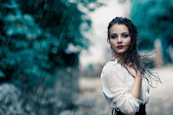 Hermosa chica de pie bajo la lluvia