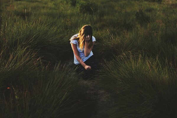 The girl in the grass in the clearing is grieving