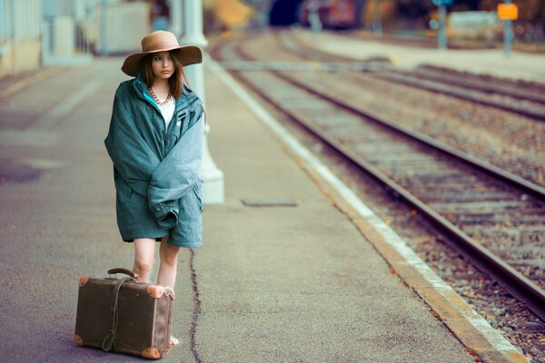 Schönes Mädchen am Bahnhof mit Koffer