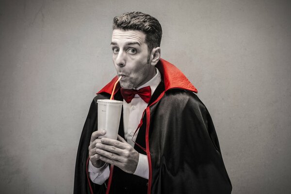 Un homme dans un costume de Dracula boit le jus de conduits