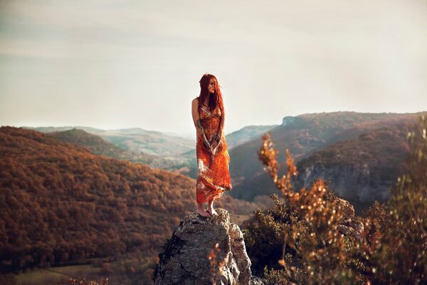Chica con vestido naranja en la piedra