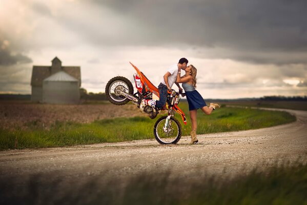 Le gars assis sur la moto, embrasse la jeune fille