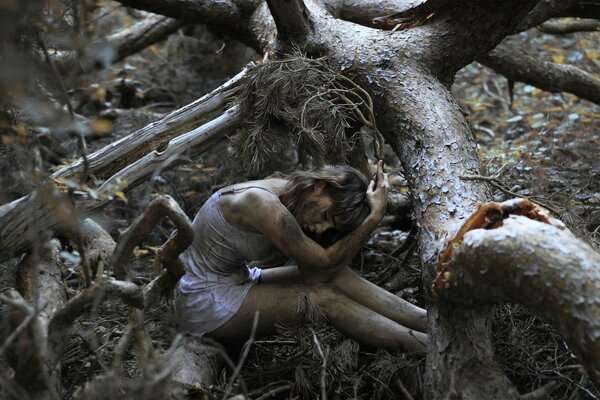 Красивая девушка сидит в грязном лесу, кругом деревья