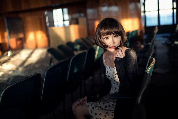 A beautiful girl with a square is sitting in an empty hall