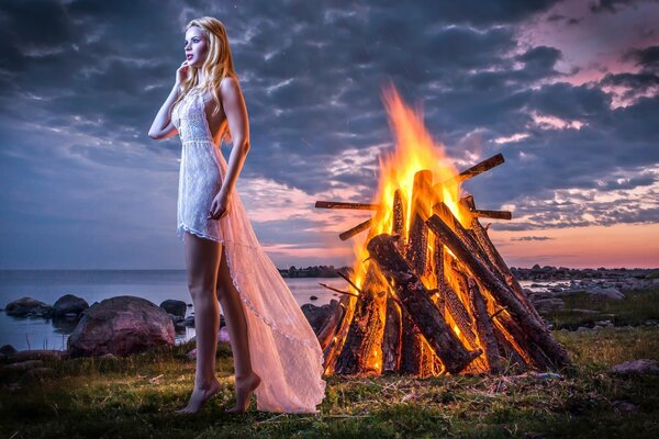 A girl in a white dress near the campfire