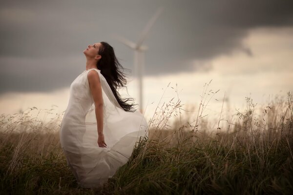 A girl in a white dress on the background of a windmill