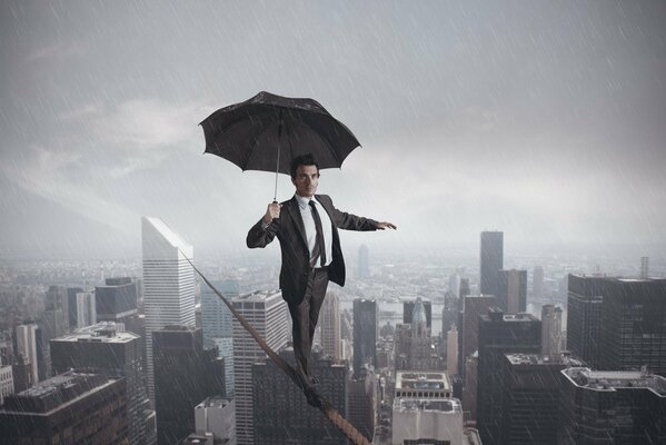 A man with an umbrella walks on a rope in the rain