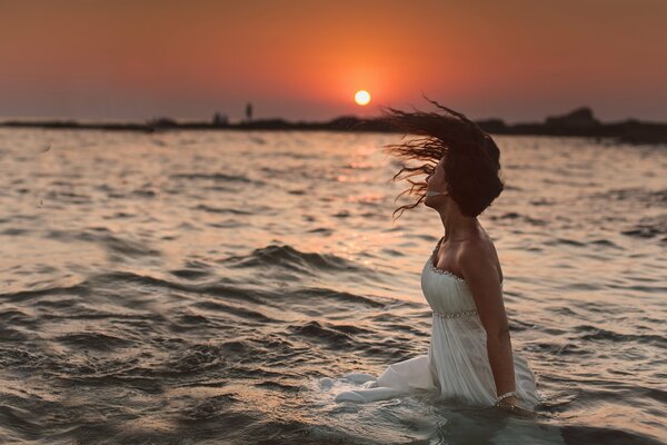 Dziewczyna w wodzie podziwia Zachód słońca