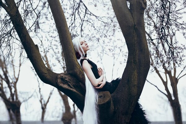 Mädchen mit langen weißen Haaren und schwefeligem Kleid ena Baum