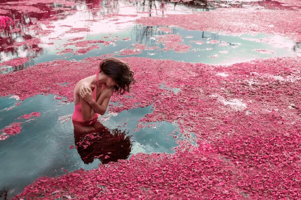 Mädchen im Wasser mit rosa Blütenblättern