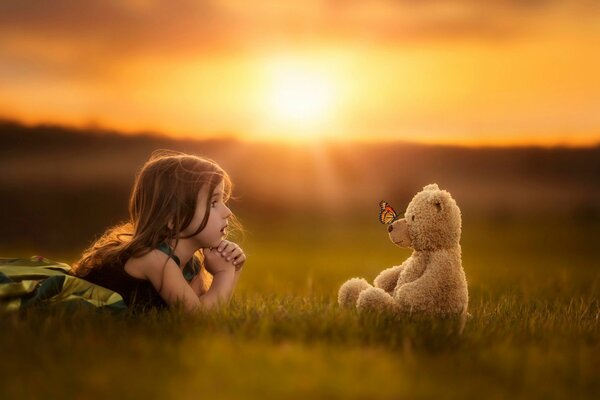 Bebé y oso de peluche en una brillante puesta de sol