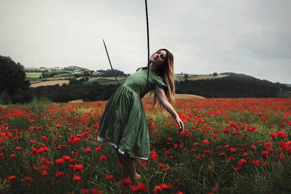 A girl in a green dress in a field with poppies