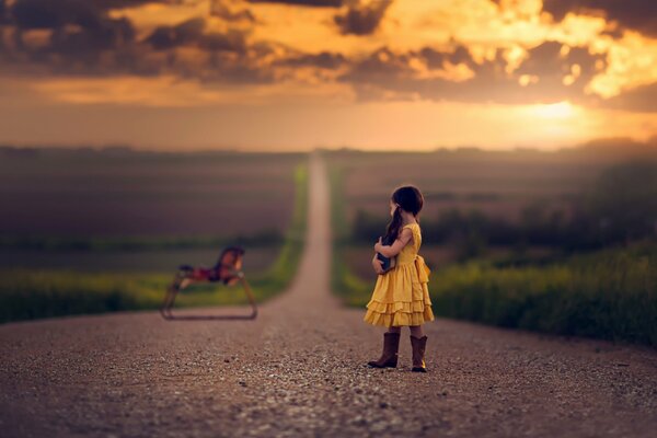La petite fille dans ses bottes sur la route regarde le jouet de cheval