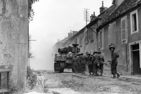 Los soldados van tras un tanque en medio de la devastación