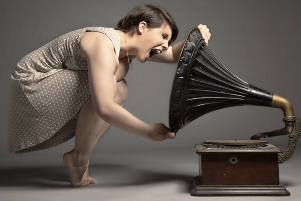 La jeune fille crie dans le gramophone sur un fond sombre