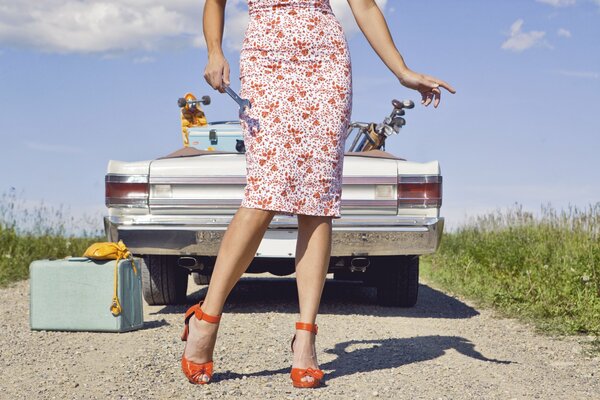 Coche retro con maleta retro y chica con llave en la mano