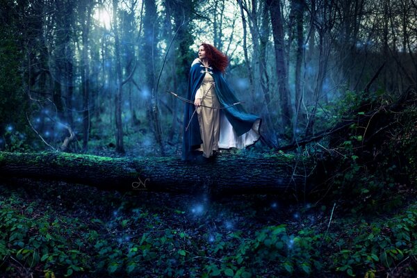 Rousse de la jeune fille dans les bois avec un arc dans les mains