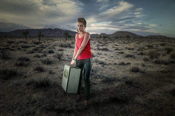 Ragazza con valigia nel deserto