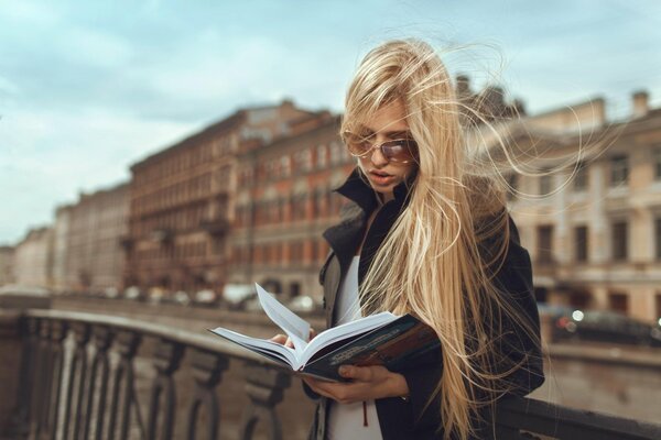 A girl is reading a book on the street
