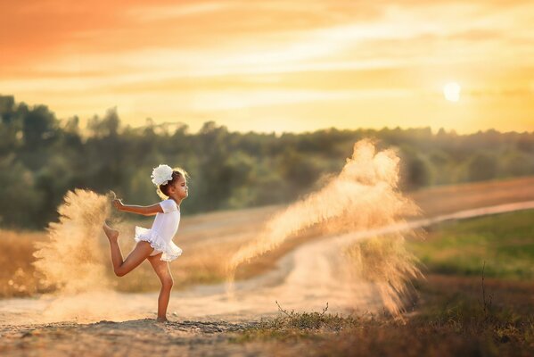 Chica bailando en un camino de arena