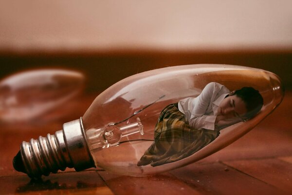 The girl is lying in an elongated light bulb