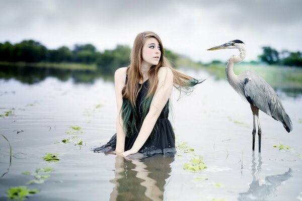 Dziewczyna w wodzie patrzy na dużego ptaka