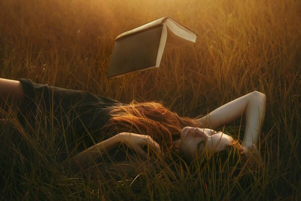 La jeune fille lit парящую un livre allongé dans l herbe