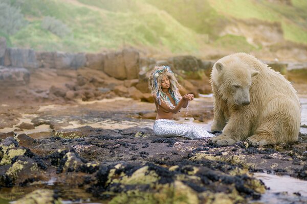 A girl and a polar bear are sitting on the rocks