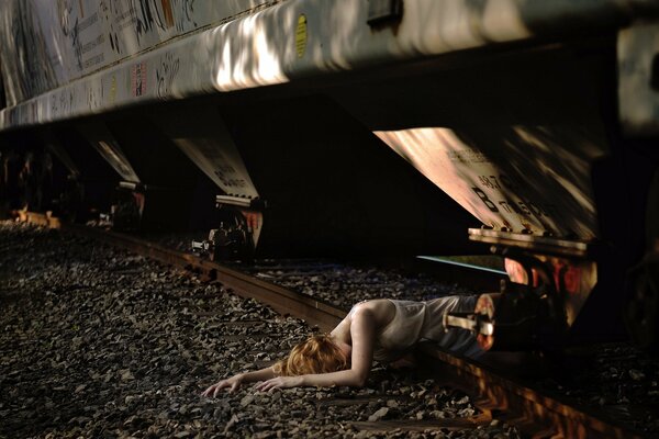 Ragazza sdraiata sui binari sotto il treno