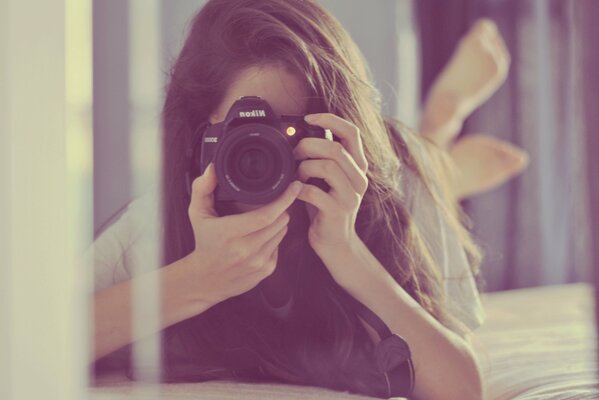 A girl with a camera is reflected in the mirror