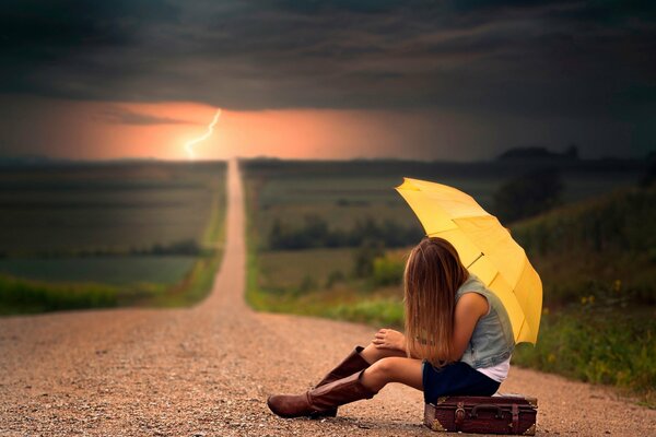 La photo de la fille avec le parapluie sur la route