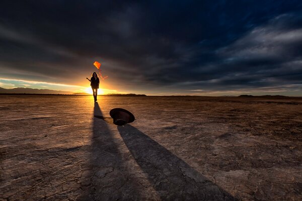 A girl with a kite in the desert