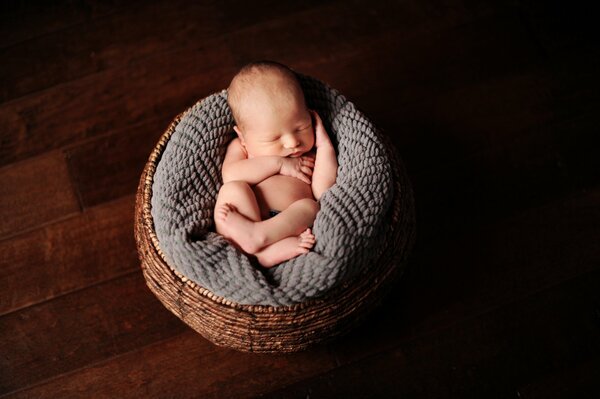 Bambino che dorme nel cestino