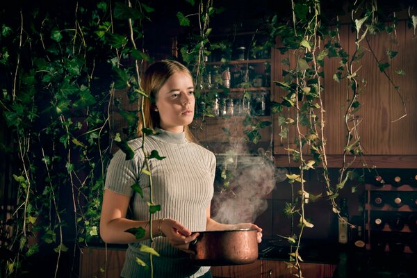 Chica con una olla en sus manos en el fondo de las plantas