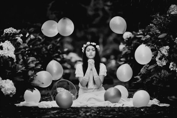 Black and white photo of a girl in a white dress among balloons