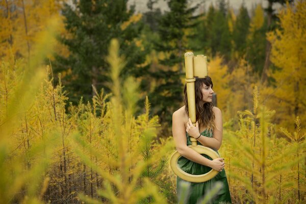Chica con una llave en el fondo del bosque de otoño