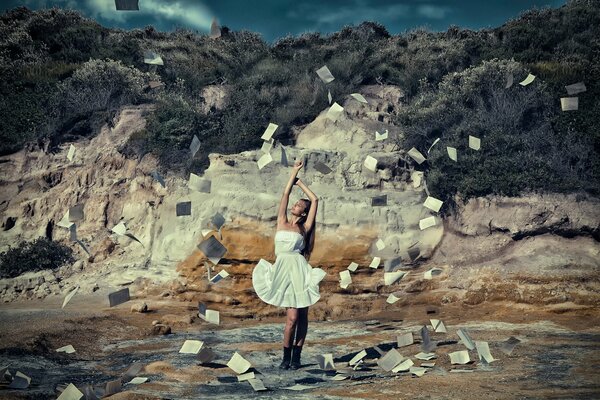 A girl in a white dress fluttering in the wind, leaves of books flying around