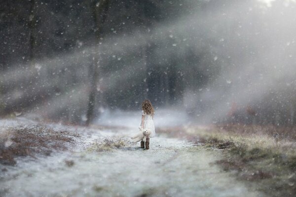 A girl in a white dress walks under the snow