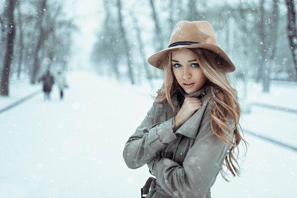 A snow-covered street in Russia, in the foreground a girl in a coat and hat