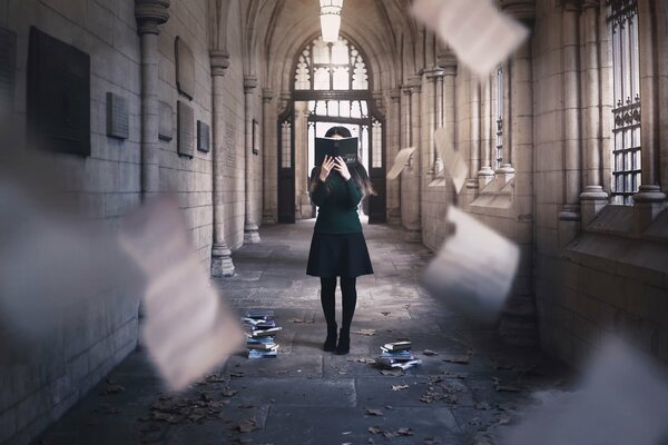 Chica en vestido oscuro con un libro en la cara