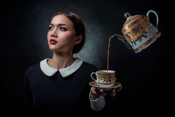 Bouilloire verse à la fille d un verre sur fond noir