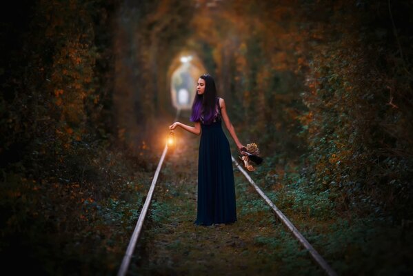 La jeune fille au coucher du soleil va par le chemin de fer