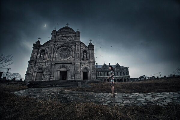 A girl in a beautiful dress against the background of a gloomy monastery