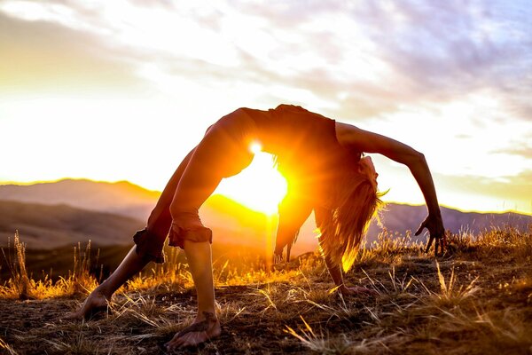 Girl in the bridge pose at sunset