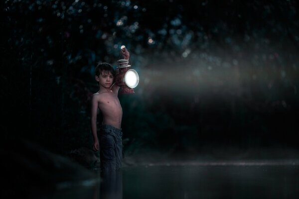 Chłopiec w mroku z latarnią w rękach